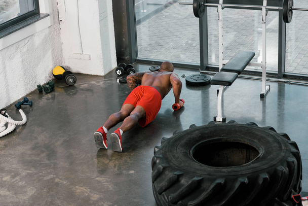 μεγάλη γωνία θέα αφροαμερικάνος αθλητής κάνει push ups με βαράκια στο γυμναστήριο - Φωτογραφία, εικόνα