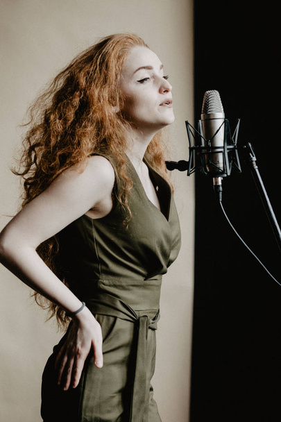 Όμορφο τραγούδι κορίτσι με το μικρόφωνο στο studio - Φωτογραφία, εικόνα