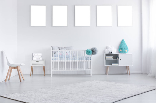 Mockup of empty posters above cradle in white baby's room interior with chair and carpet. Real photo - Фото, изображение