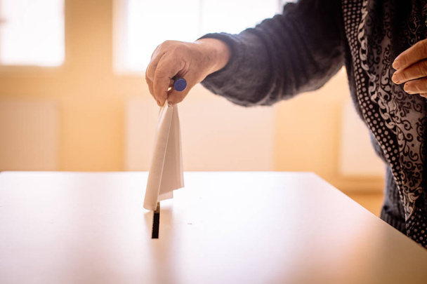 Immagine a colori di una persona che lancia un voto in un seggio elettorale, durante le elezioni. - Foto, immagini