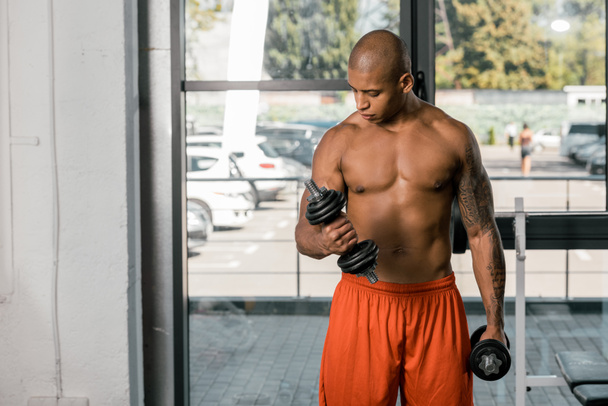 handsome african american sportsman exercising with dumbbells at gym - Photo, Image