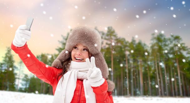 happy woman taking selfie over winter forest - Foto, imagen