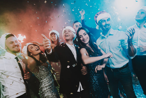 People in Santa Claus Cap Celebrating New Year. Happy New Year. People Have Fun. Indoor Party. Celebrating of New Year. Young Woman in Dress. Young Man in Suit. Happy People. Red Cap. - Photo, Image