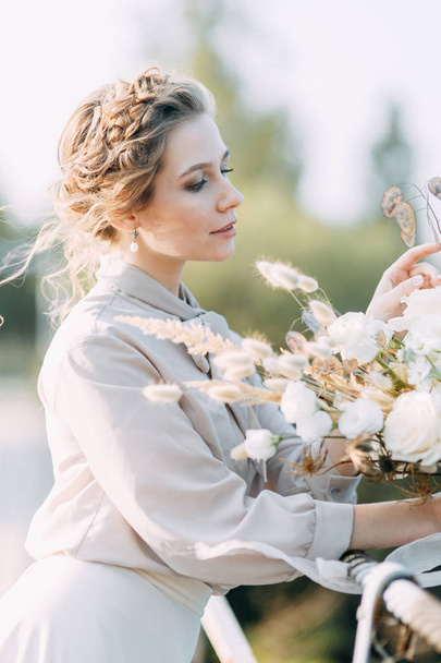 花や装飾と結婚式のアーチの前で美しい花嫁。手に花束と詳細。女の子は、笑顔と踊り満足しています。現代風の夢のウェディングドレス - 写真・画像