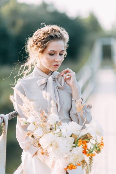 Beautiful bride in front of wedding arch with flowers and decor. Bouquet in the hands and details. The girl is happy, smiling and dancing. Dream wedding dress in modern style - 写真・画像