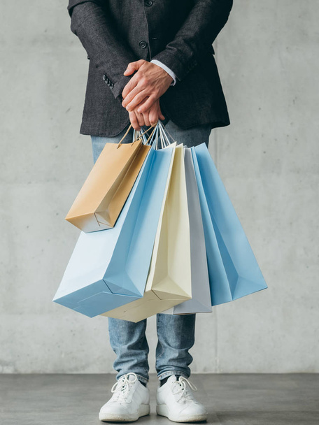 black friday shopping. store sales and discounts. man holding multiple bags with goods in hands. - Foto, imagen