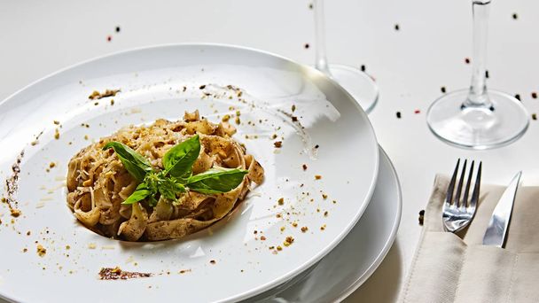 Tagliatelle with mushrooms and decorated with basil leaves. - Foto, afbeelding