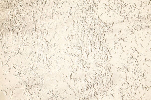 Beige facade plaster background. Single-layer monolithic gypsum decorative background. Monolayer glued wallpaper from cement plaster. The appearance of the structure of the building. Silicate sand Cement plaster. Copy space - 写真・画像