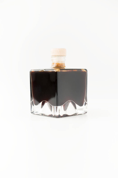Vinagre balsámico de Módena en botellas cuadradas de vidrio apilable aisladas sobre fondo blanco
. - Foto, imagen