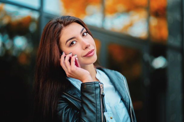 Business woman with smartphone close up near office building. Girl have conversation with cell phone. Beautiful caucasian young woman talking with mobile device. - Zdjęcie, obraz