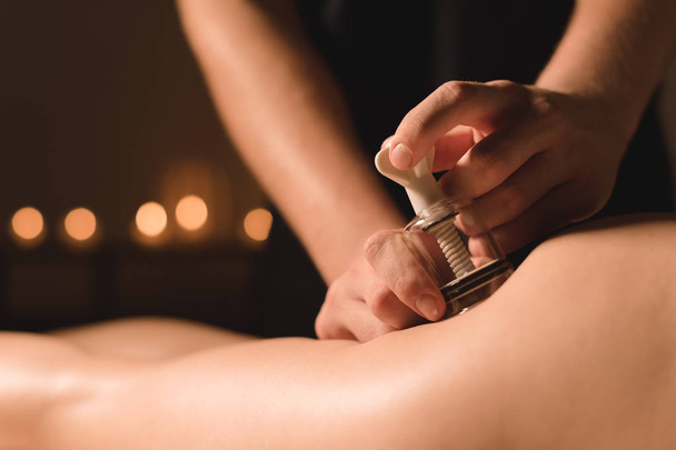 Close-up Hardware cosmetology. Vacuum massage procedure. Male hands install vacuum banks. Close-up of anti-cellulite treatment of a young woman - Photo, image
