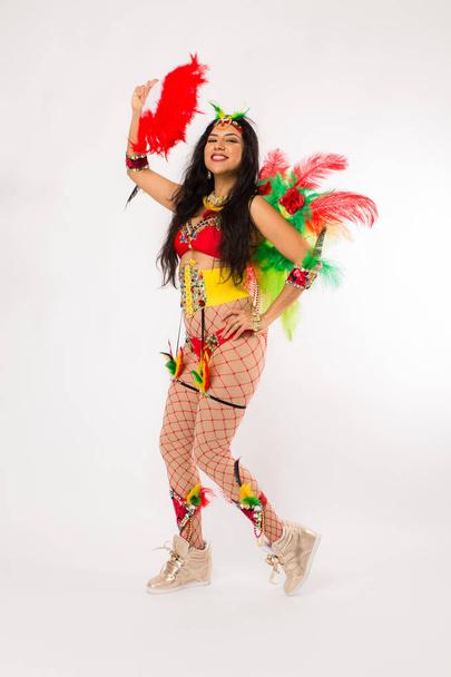 Very fit young hispanic woman in Carnaval costume and athletic shoes posing on clean white background - Фото, изображение