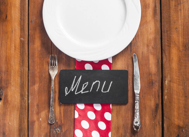Étterem menü design. Éttermi menü üres tányért és evőeszközöket, fából készült háttér színes szalvéta. Szemközti nézet másolása adható szöveg - Fotó, kép
