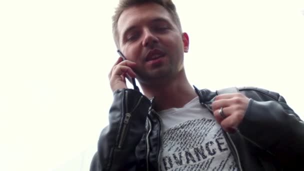 Handsome young man standing on the street and talking on the smartphone. - Filmmaterial, Video