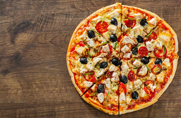 Pizzę i pokrojone mięso z kurczaka, ser Mozzarella, pomidor, oliwek. Włoskiej pizzy na podłoże drewniane - Zdjęcie, obraz