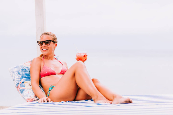 Jonge vrouw drinken cocktail in een strandbar - Foto, afbeelding