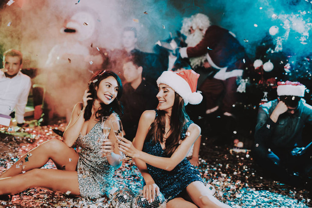 Két fiatal nők ünnepli az új év fél. Santa Claus Cap. Az emberek piros sapkát. Boldog új évet koncepció. Pohár pezsgő. Ünnepli új évet koncepció. Fiatal nő ruha. - Fotó, kép