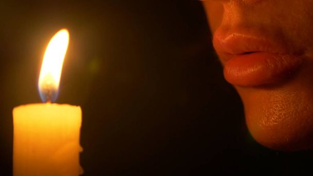 The woman with burning candle. close-up, female lips, whispering at the candle flame. - Foto, imagen