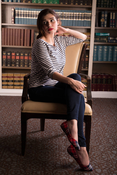 Jovem caucasiana vestida como Jackie Kennedy posa em uma biblioteca
 - Foto, Imagem