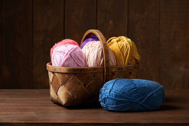 красочные шерстяные нити для вязания в корзине, деревянный фон
 - Фото, изображение