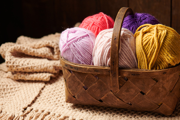 kleurrijke wollen draden voor breien in de mand, houten achtergrond - Foto, afbeelding