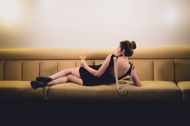 Young caucasian woman dressed like Audrey Hepburn poses in an empty bar - Photo, Image