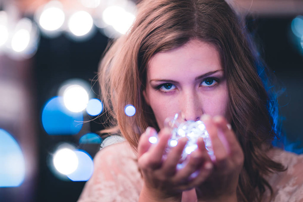 Attractive young caucasian woman poses with string lights with heavy bokeh - Photo, Image