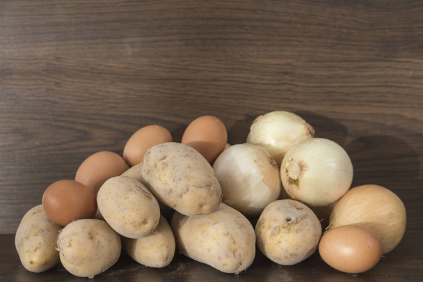 Zwiebeln, Kartoffeln und Eier, Zutaten für Kartoffelomelett auf braunem Hintergrund - Foto, Bild