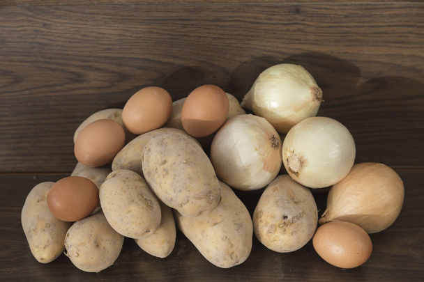 Zwiebeln, Kartoffeln und Eier, Zutaten für Kartoffelomelett auf braunem Hintergrund - Foto, Bild