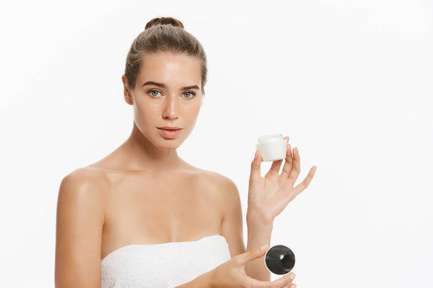 Mulher bonita aplicando tratamento de creme cosmético em seu rosto isolado no fundo branco
 - Foto, Imagem