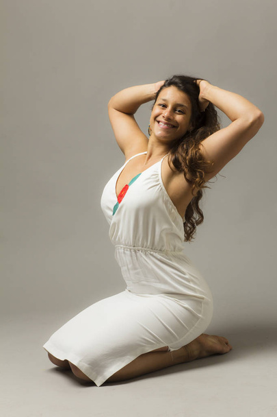 young beautiful woman posing in studio wearing white dress  - Фото, изображение