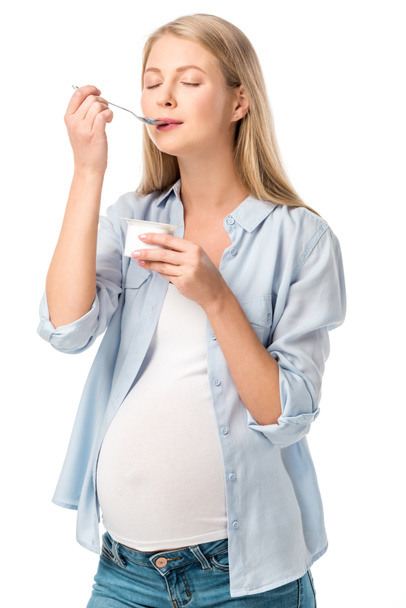 atrakcyjna kobieta w ciąży z zamkniętymi oczami Jedzenie jogurtu na białym tle - Zdjęcie, obraz