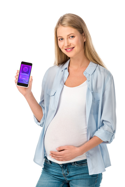 mooie blonde zwangere vrouw toont smartphone met shopping app geïsoleerd op wit - Foto, afbeelding