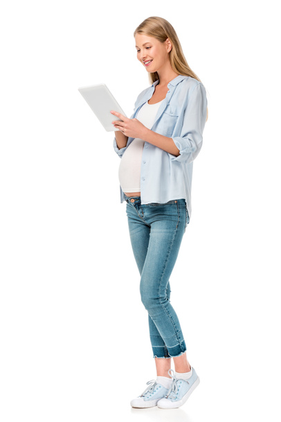 ελκυστική γυναίκα έγκυος χρησιμοποιώντας ψηφιακό tablet που απομονώνονται σε λευκό - Φωτογραφία, εικόνα