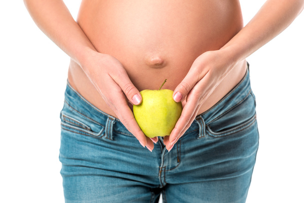 vista recortada de la mujer embarazada sosteniendo manzana sana fresca cerca de su vientre aislado en blanco
 - Foto, Imagen
