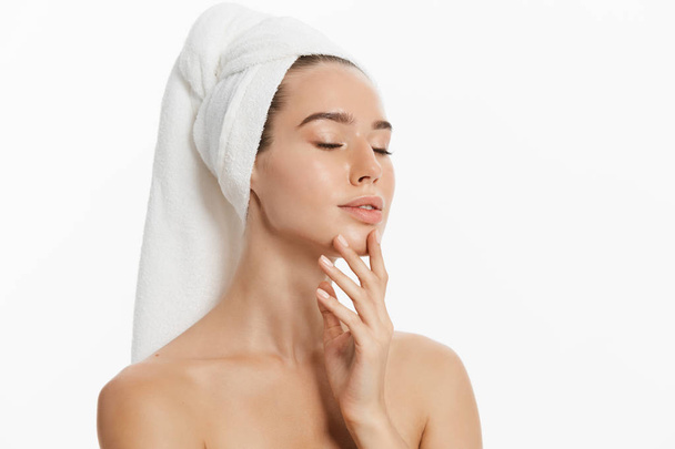 happy young girl with clean skin and with a white towel on her head washes face - Photo, Image