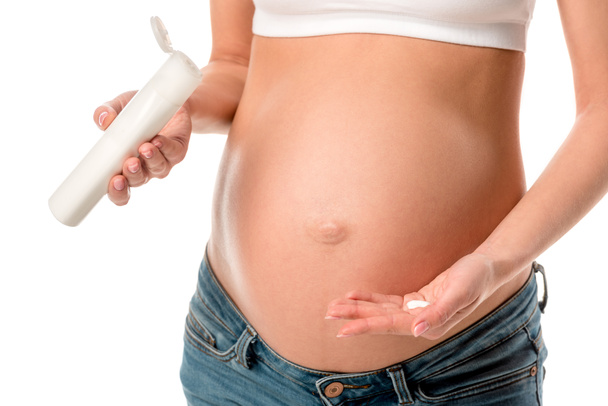 terhes nő kozmetikai krém alkalmazása a pocakját, elszigetelt fehér csíkok elkerülésére levágott megtekintése - Fotó, kép