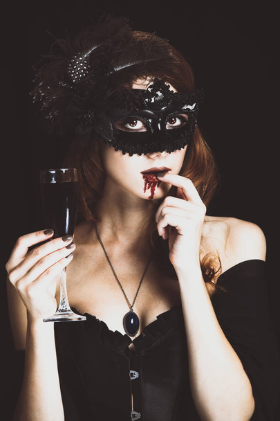Redhead vampire woman in mask with glass of blood. - Foto, Imagen