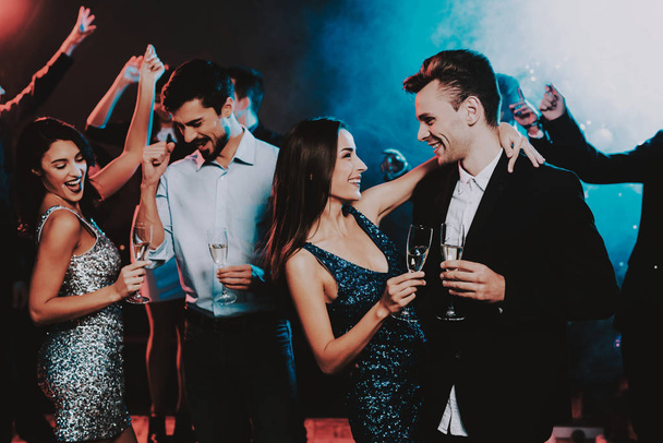 Happy Young People Dancing on New Year Party. Happy New Year Concept. Glass of Champagne. Celebrating of New Year. Young Woman in Dress. Young Man in Suit. Happy People. Modern Dances. - Foto, afbeelding