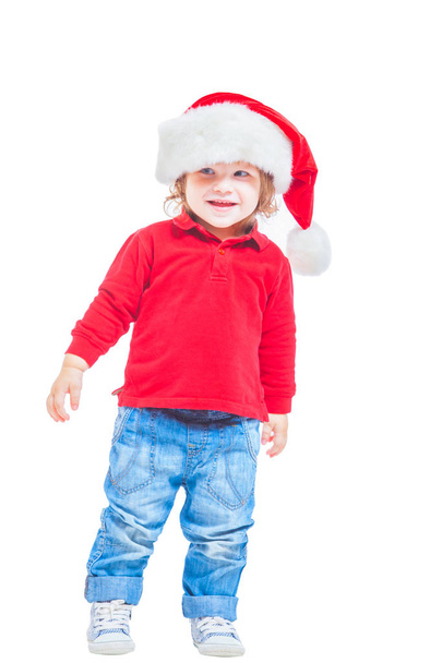 Christmas. A little boy in a Santa hat, in a red jacket and blue jeans. Isolated on white background. - Foto, imagen