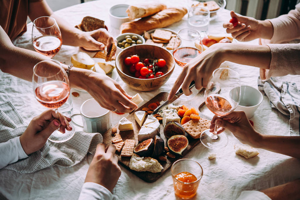 Friends having a dinner party with different kinds of appetizers and rose wine. - Foto, afbeelding