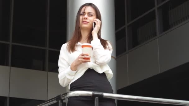 Üzletasszony használ a smartphone beszélő forró itallal - Felvétel, videó