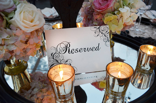 Κράτησης συνδεθείτε με γαμήλια ανθοδέσμη και ποτήρια στο τραπέζι, όμορφη γαμήλια δεξίωση ειδικά καθίσματα σημάδι στην καλλιγραφία, Δημ ρομαντικό φωτισμό και φρέσκα λουλούδια - Φωτογραφία, εικόνα