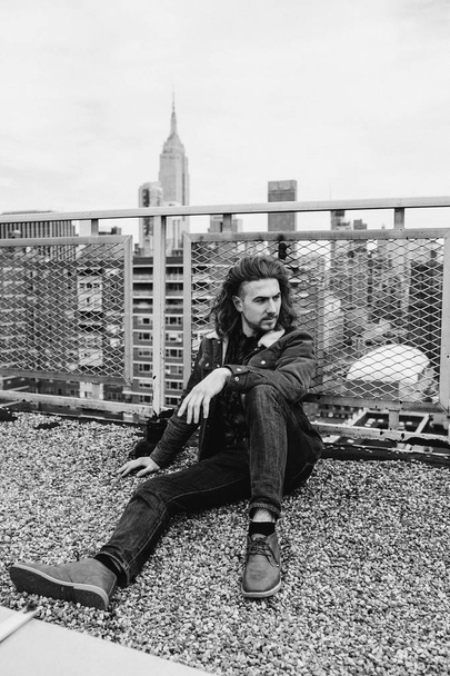 Bearded hipster sitting on rooftop in New York city, Manhattan, USA. Black and white photo - Fotoğraf, Görsel