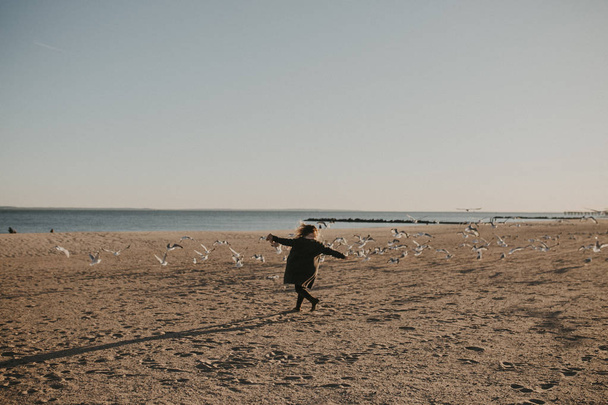 A girl run on the beach with with birds - Zdjęcie, obraz