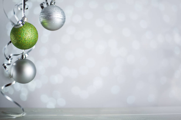 Срібні та зелені новорічні кульки з кучерявим стрічковим луком на блискучому фоні боке з копіювальним простором для тексту
 - Фото, зображення