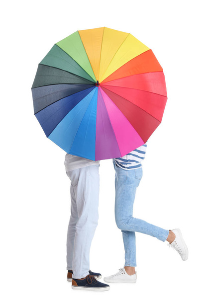 Couple hiding behind rainbow umbrella on white background - Photo, image