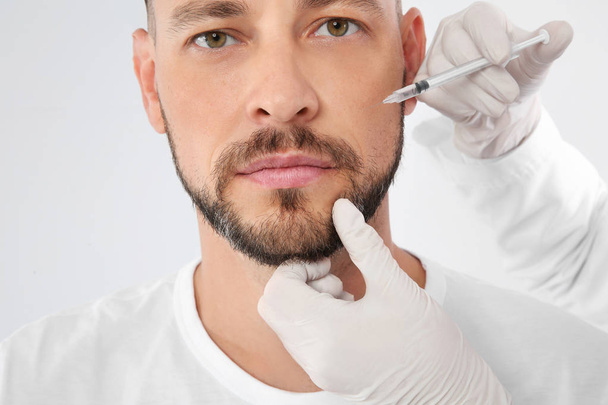 Man getting facial injection on white background, closeup. Cosmetic surgery concept - Foto, Imagem