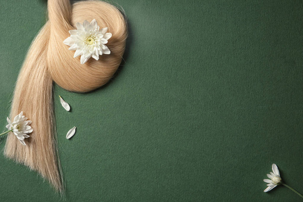 Composition with lock of blond hair and flowers on color background, top view. Space for text - Фото, зображення