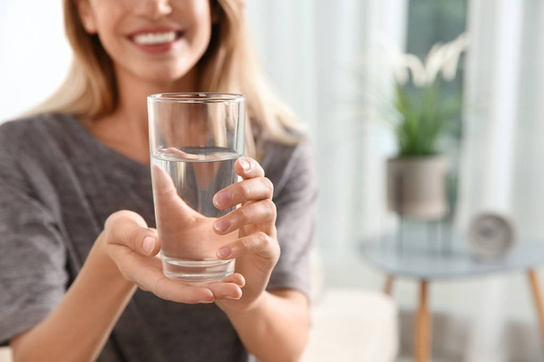 Woman holding glass with clean water at home, closeup. Space for text - Fotó, kép